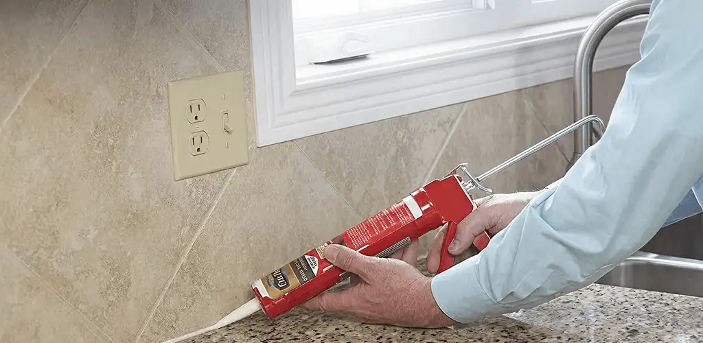 Handyman applying caulk along a kitchen backsplash and countertop seam in Lakeland, FL