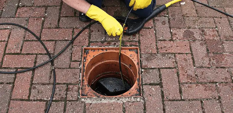 Drain cleaning technician using a drain snake to clear a clogged drain in Lakeland, FL