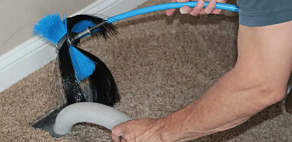 Dryer vent cleaning technician brushing lint from a vent line in Lakeland, FL