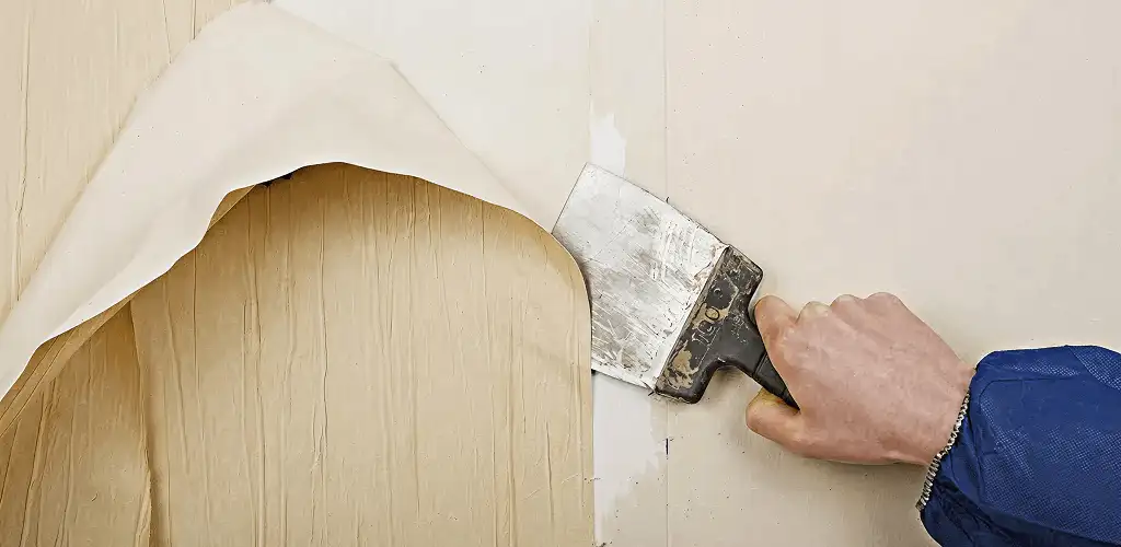 Handyman removing wallpaper with a scraper for wall preparation in Lakeland, FL