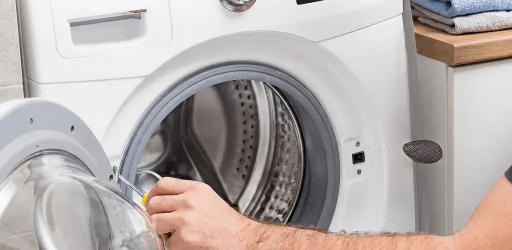 Handyman repairing a front-load washing machine and inspecting the drum in Lakeland, FL