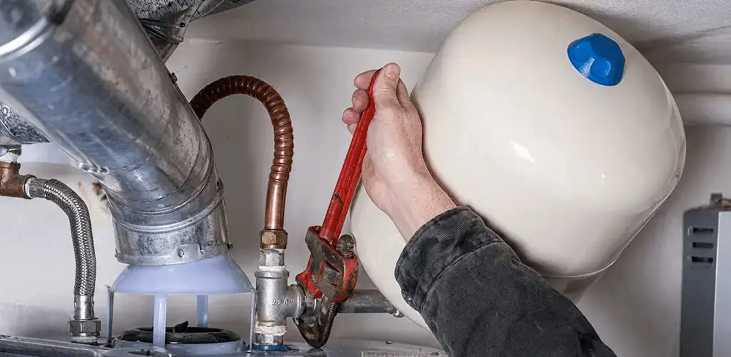 Water heater repair technician tightening plumbing connections near a tank unit in Lakeland, FL