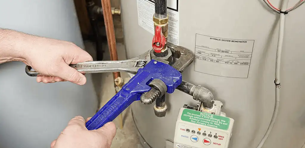 Water heater repair technician tightening the shutoff valve and supply line in Lakeland, FL
